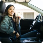 Young driver buckles her seatbelt and smiles.